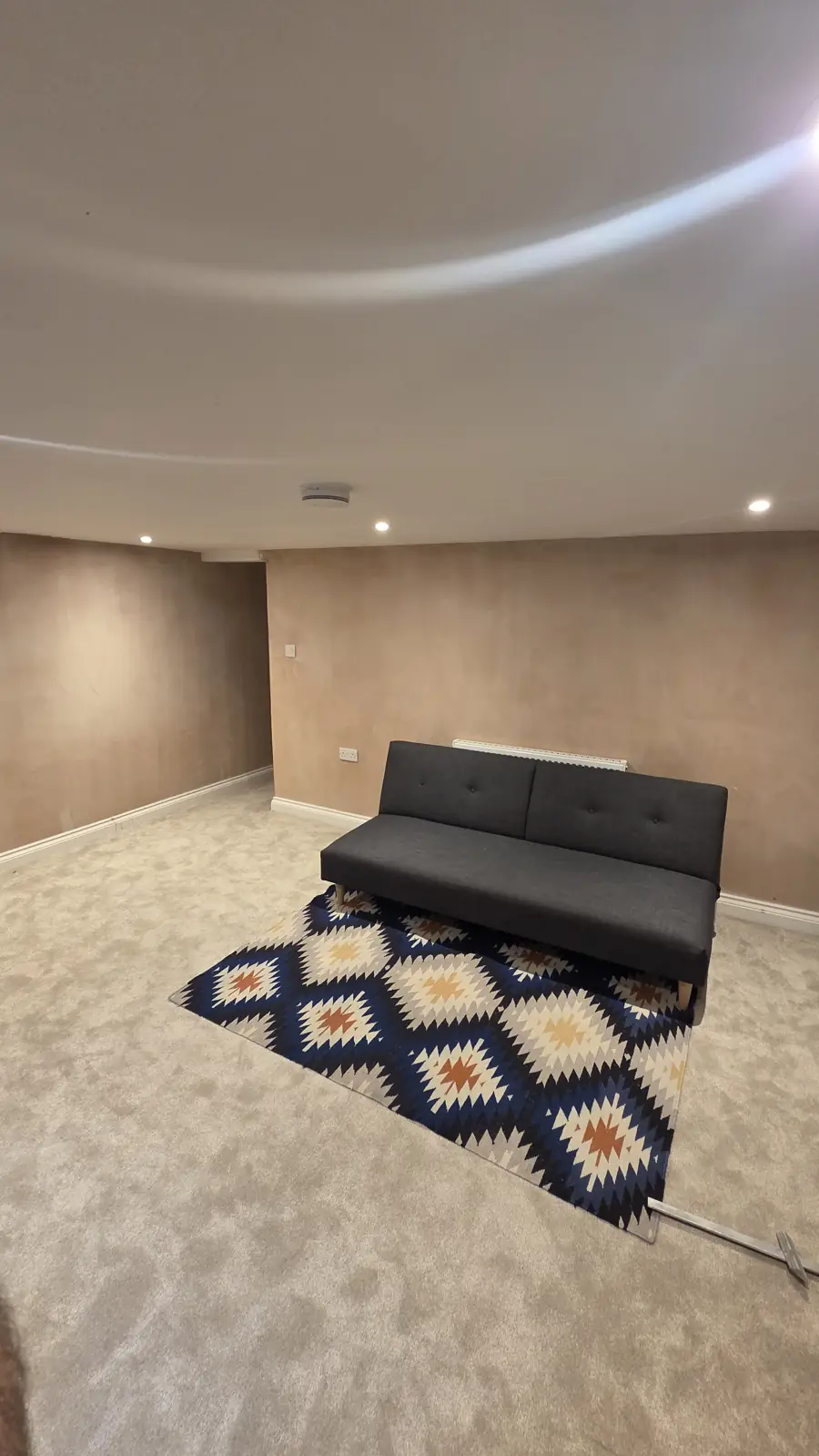 Finished basement room in Faversham with smooth plastered walls, carpet and a sofa