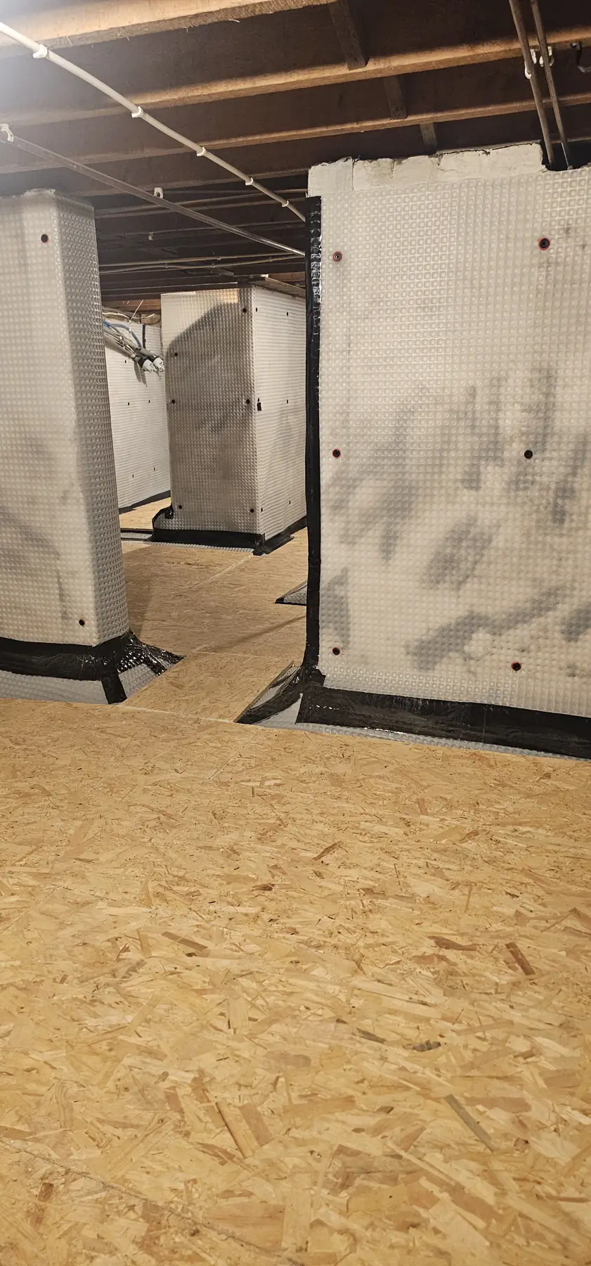 Brick piers wrapped in cavity drain membrane across the large basement