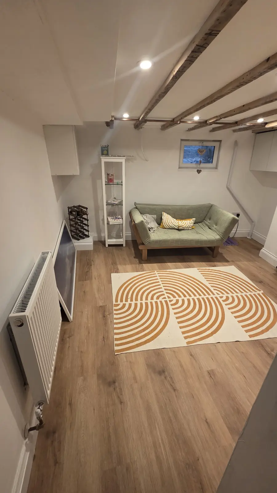 The finished cellar room with exposed beams and a radiator