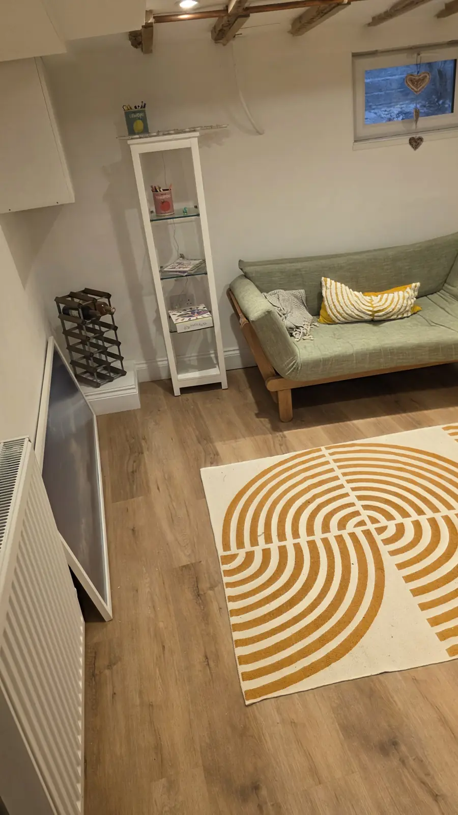 Cosy converted cellar in Faversham with a green sofa, oak floor, a patterned rug and a small window