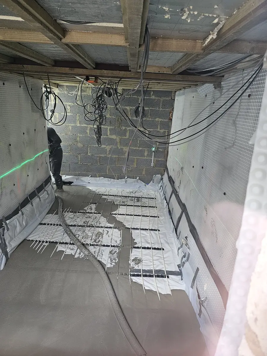 Lowered basement with cavity membrane on every wall and underfloor heating pipes being laid over the new floor