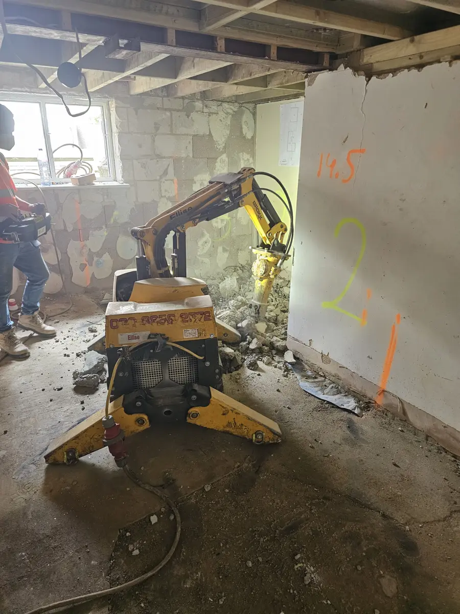 Remote-controlled demolition robot breaking out the old basement floor