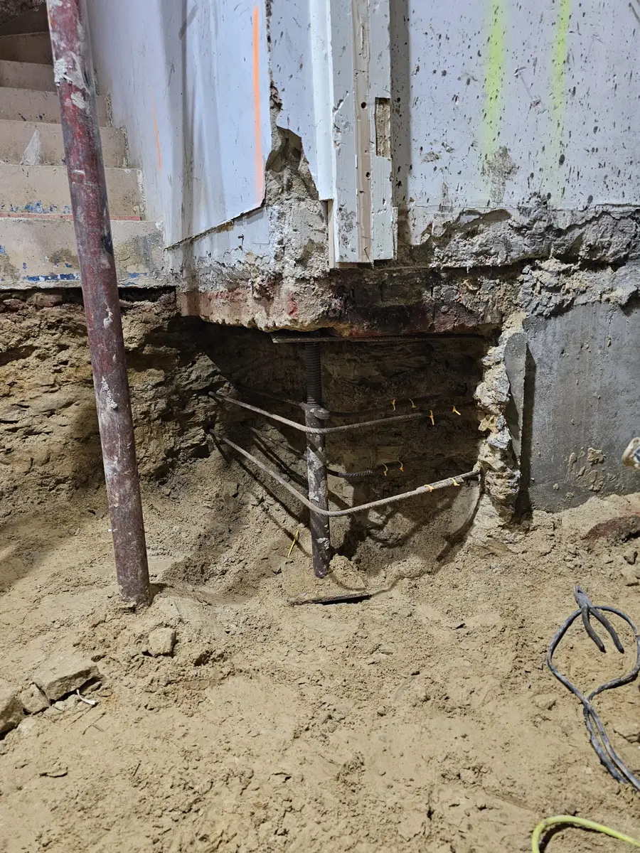 An underpinning section dug beneath the existing wall with steel reinforcement in place, propped and ready for concrete