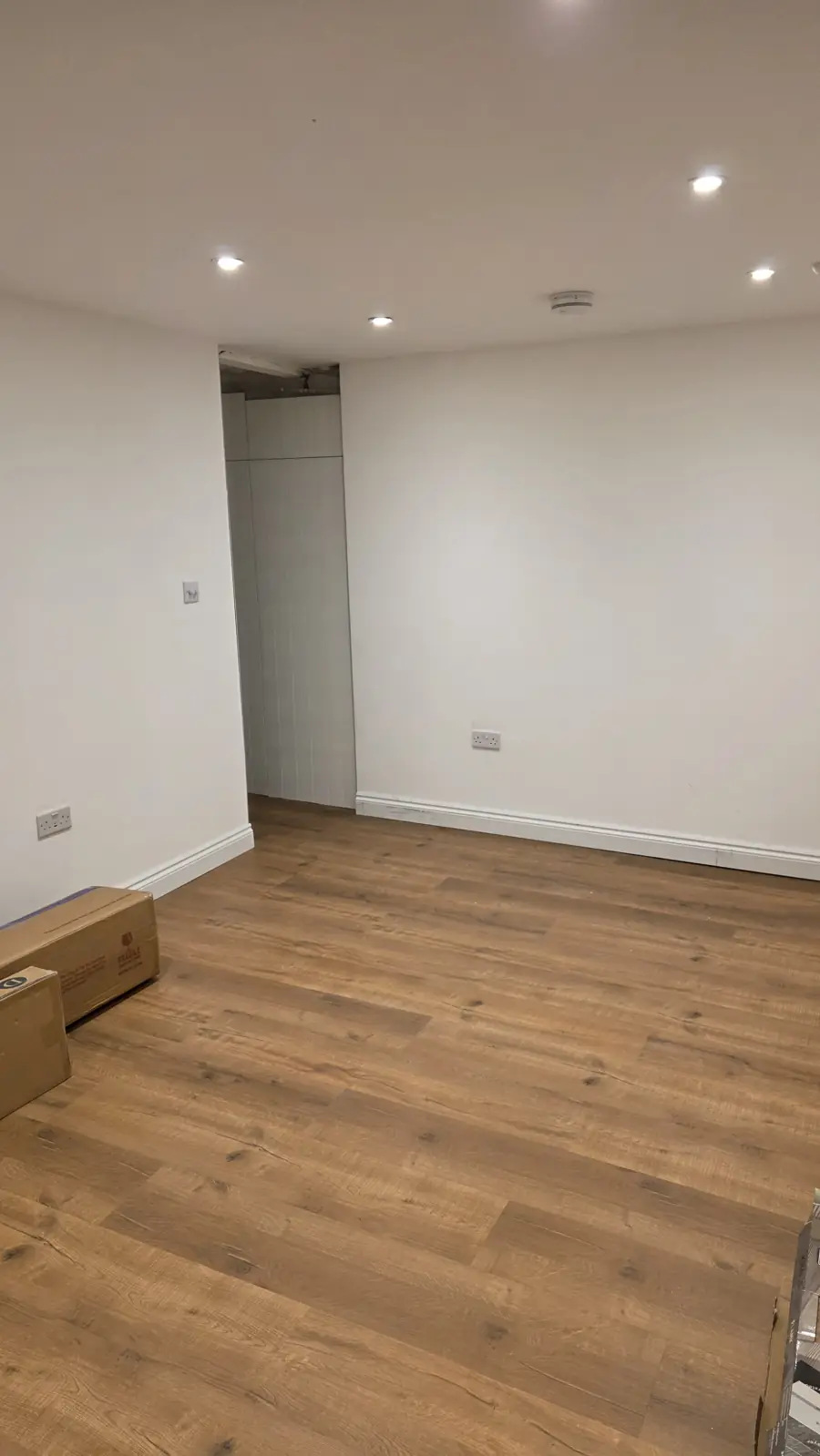 Finished basement bedroom in Maidstone with white walls, downlights and oak-effect flooring